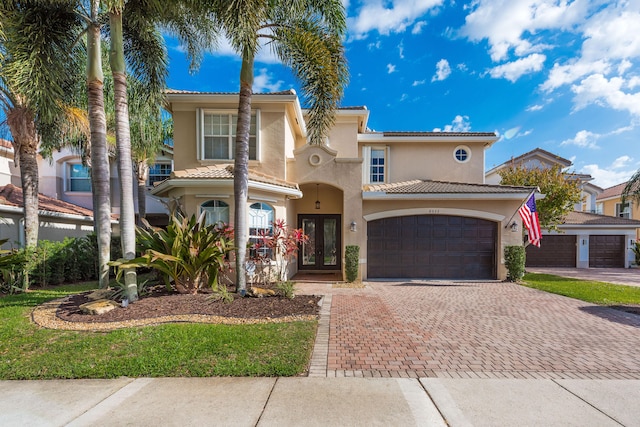8533 Briar Rose Pt, Boynton Beach, FL 33473 - mediterranean / spanish-style house featuring french doors, decorative driveway, stucco siding, an attached garage, and a tiled roof