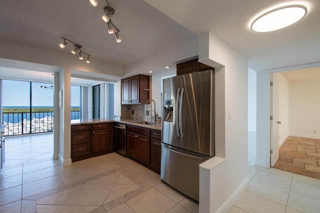 kitchen featuring baseboards, light stone counters, appliances with stainless steel finishes, and a sink