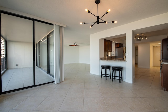 interior space with a sink, a chandelier, light tile patterned floors, a breakfast bar, and freestanding refrigerator