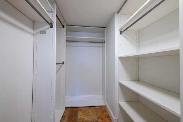walk in closet featuring stone finish flooring