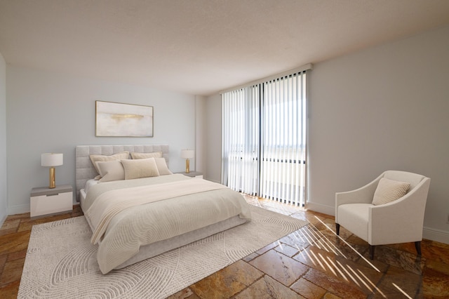 bedroom featuring access to exterior, stone tile flooring, and baseboards