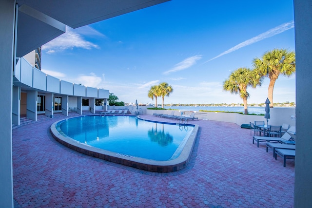 pool featuring a patio area and a water view