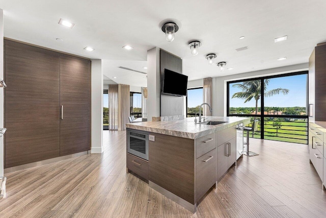 7383 Orangewood Ln Unit 304, Boca Raton, FL 33433 - kitchen with modern cabinets, a sink, light wood-type flooring, light countertops, and a center island with sink