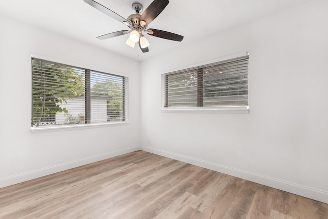 empty room with light wood-style flooring, a ceiling fan, and baseboards