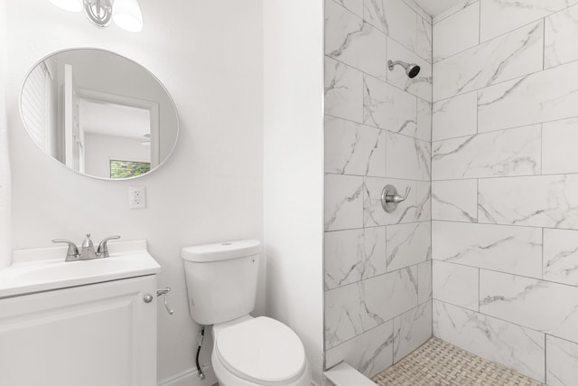 bathroom featuring toilet, vanity, and tiled shower
