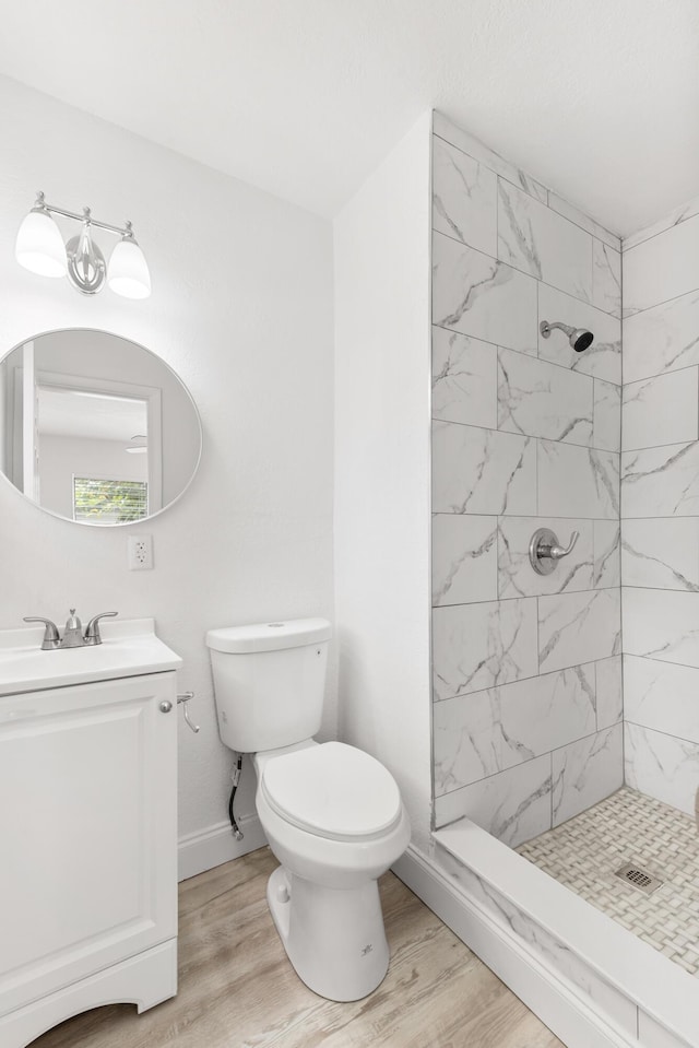 full bath featuring wood finished floors, toilet, vanity, baseboards, and a stall shower