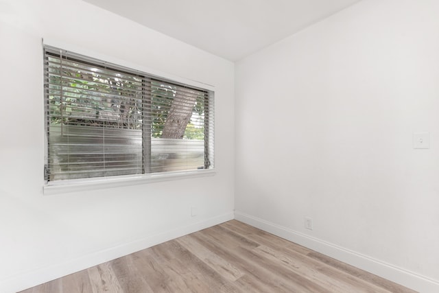 spare room featuring baseboards and wood finished floors