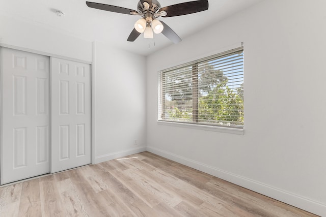 unfurnished bedroom with a ceiling fan, baseboards, a closet, and light wood-type flooring