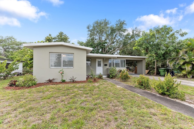 ranch-style home with a front lawn, driveway, a carport, and stucco siding