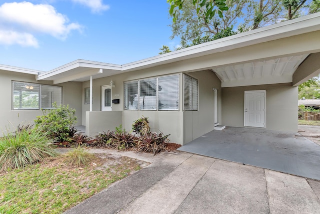 view of front of home featuring driveway, a carport, and stucco siding