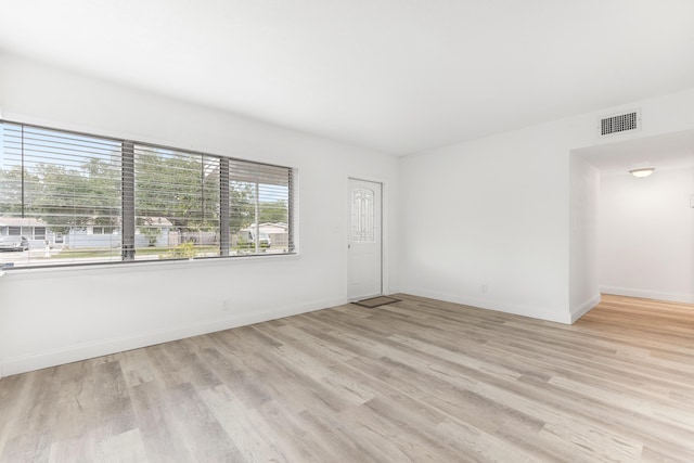 spare room with baseboards, light wood-style floors, and visible vents