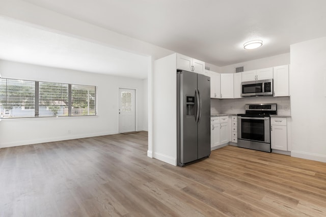 kitchen with backsplash, light wood-style flooring, appliances with stainless steel finishes, and white cabinetry