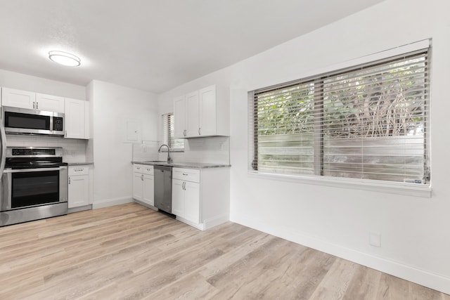 kitchen featuring backsplash, white cabinetry, stainless steel appliances, and a sink