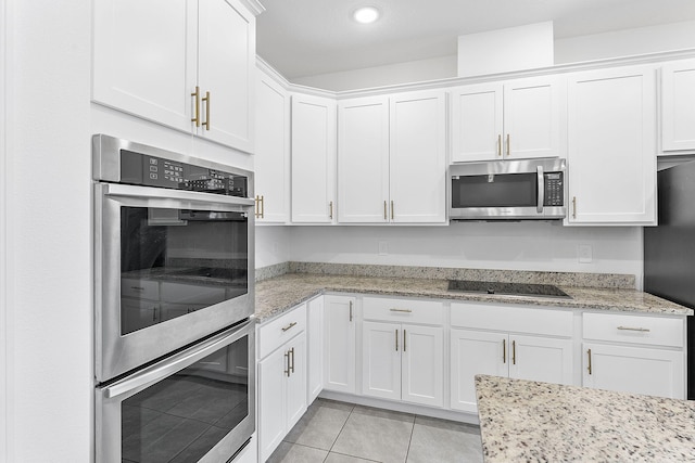 2132 SW Vista Rd, Port Saint Lucie, FL 34953 - kitchen with light tile patterned floors, stainless steel appliances, white cabinets, and light stone counters