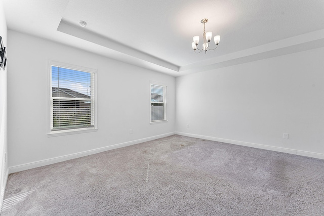 2132 SW Vista Rd, Port Saint Lucie, FL 34953 - carpeted spare room with an inviting chandelier, baseboards, and a tray ceiling