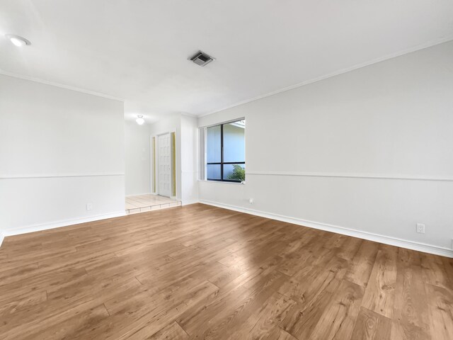 empty room featuring crown molding, wood finished floors, and visible vents