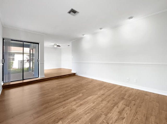 empty room featuring crown molding, wood finished floors, and visible vents