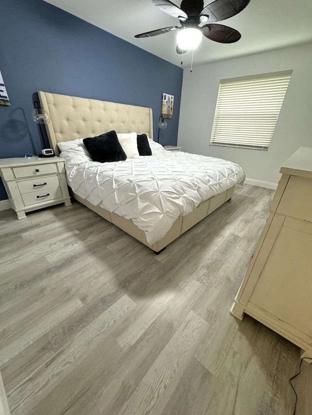 bedroom featuring baseboards, a ceiling fan, and light wood-style flooring