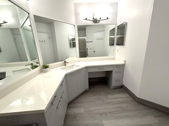 full bath with baseboards, wood finished floors, and vanity