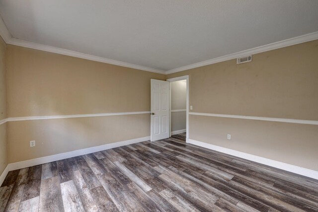 empty room with ornamental molding, visible vents, wood finished floors, and baseboards