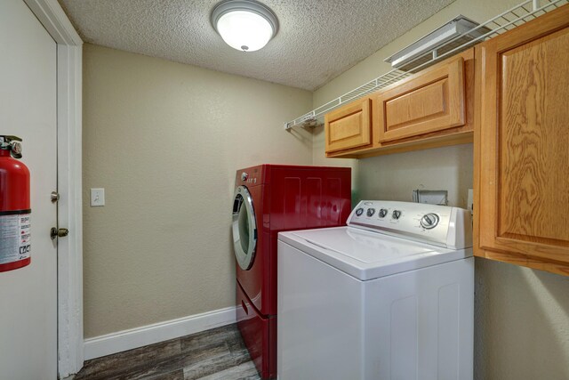 laundry area featuring independent washer and dryer, cabinet space, baseboards, a textured ceiling, and dark wood-type flooring