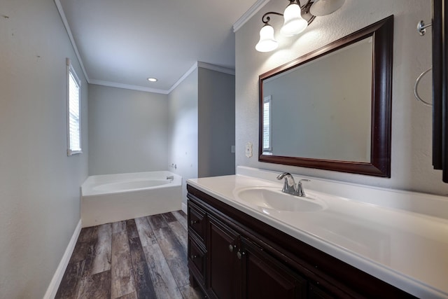 bathroom featuring baseboards, a bath, ornamental molding, wood finished floors, and vanity