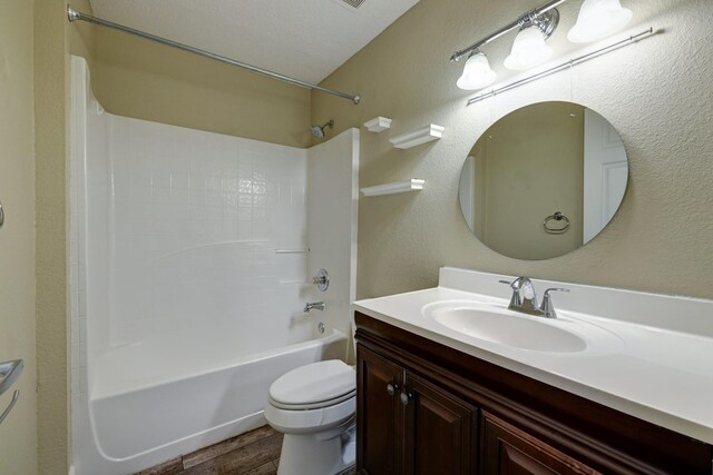 bathroom with wood finished floors, toilet,  shower combination, and vanity