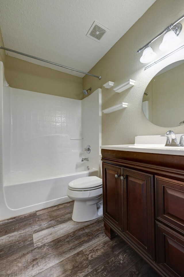 bathroom with vanity, toilet, visible vents, tub / shower combination, and wood finished floors