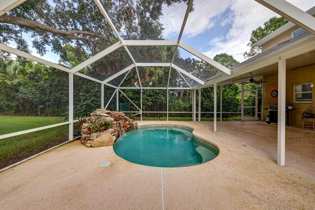 outdoor pool with a ceiling fan, a patio, and glass enclosure