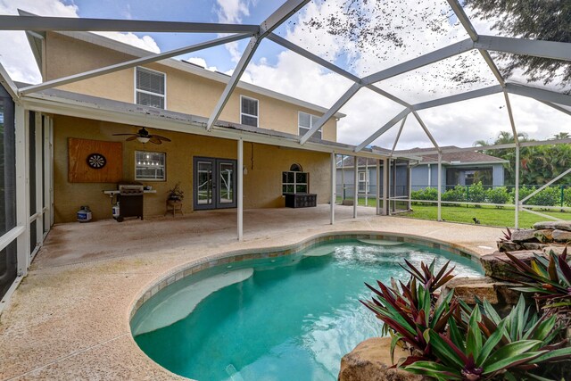 outdoor pool featuring area for grilling, a patio area, glass enclosure, a ceiling fan, and french doors