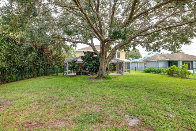 view of yard featuring glass enclosure and a fenced backyard
