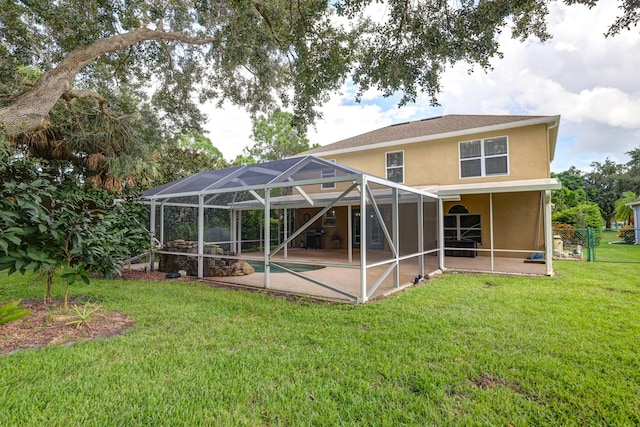 rear view of property featuring a patio, a lawn, an outdoor pool, stucco siding, and fence