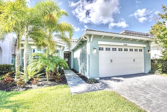 15581 Goldfinch Cir, The Acreage, FL 33470 - view of front facade featuring stucco siding, an attached garage, and decorative driveway