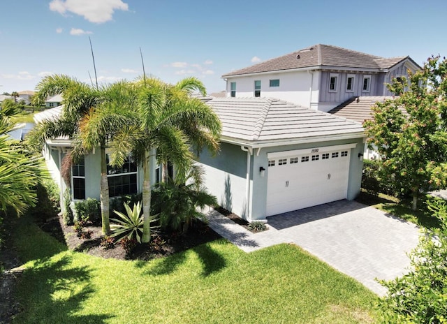 15581 Goldfinch Cir, The Acreage, FL 33470 - view of front of house featuring a garage, a tile roof, driveway, stucco siding, and a front lawn