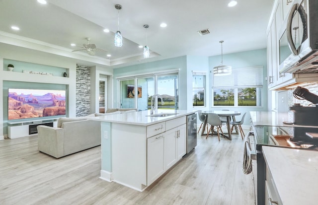 15581 Goldfinch Cir, The Acreage, FL 33470 - kitchen featuring appliances with stainless steel finishes, a sink, light wood-style flooring, open floor plan, and white cabinets