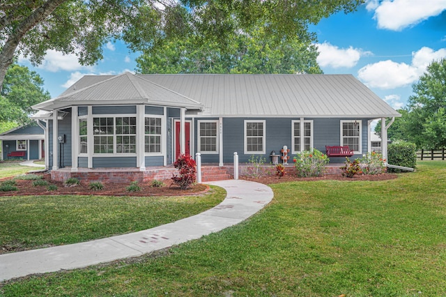 ranch-style house with a front lawn, metal roof, and covered porch
