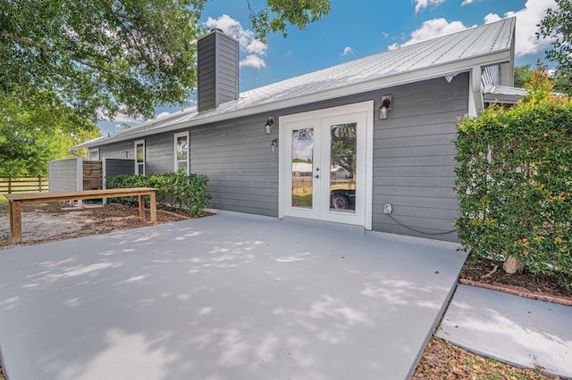 back of property with fence, a chimney, french doors, and a patio