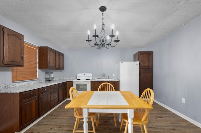 kitchen with dark wood-style floors, a sink, white appliances, baseboards, and a notable chandelier