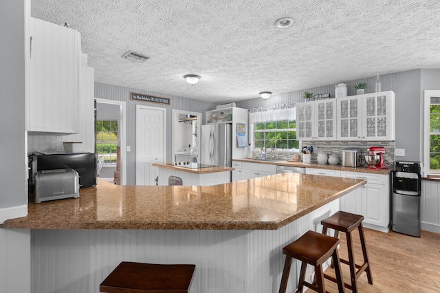 kitchen featuring a peninsula, white cabinetry, stainless steel appliances, and visible vents