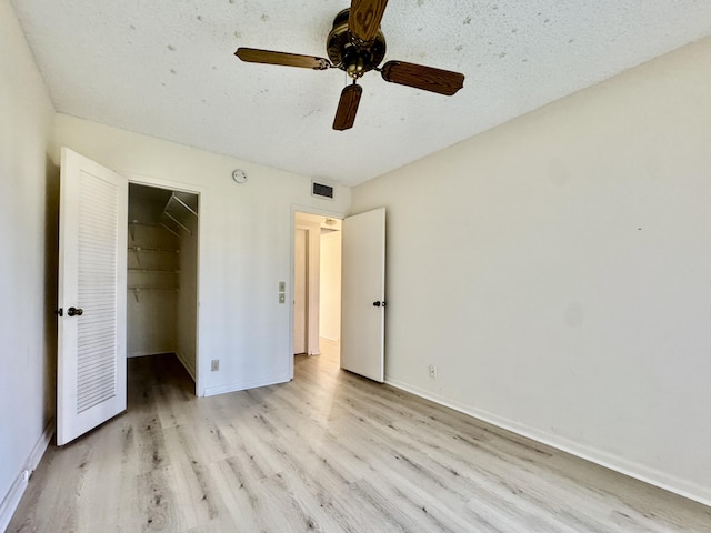 82 Dorset Unit B, Boca Raton, FL 33434 - unfurnished bedroom featuring light wood-style floors, a walk in closet, a closet, a textured ceiling, and ceiling fan