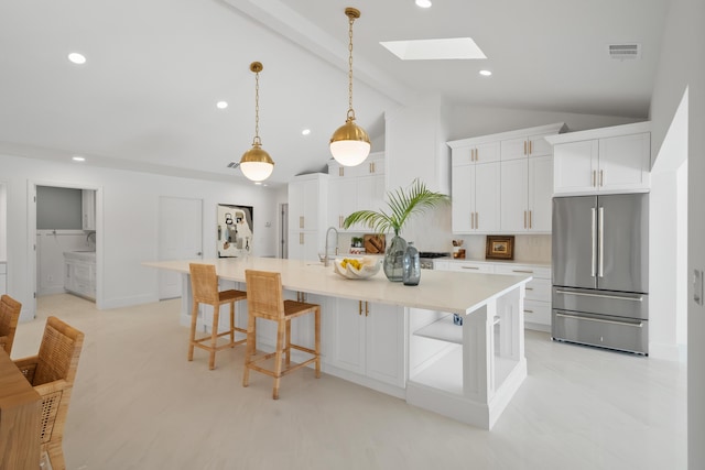 kitchen with visible vents, white cabinets, a skylight, and freestanding refrigerator