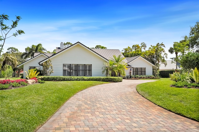 ranch-style home with a chimney, curved driveway, and a front yard