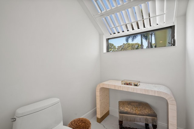 bathroom with baseboards, toilet, and marble finish floor