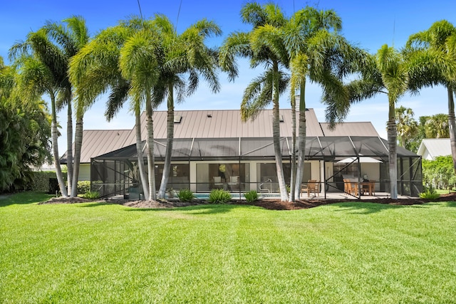 back of house with metal roof, a yard, and a lanai