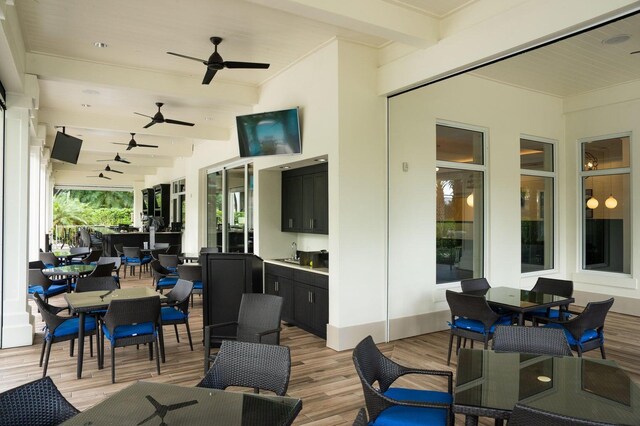 view of patio / terrace with a deck, ceiling fan, outdoor dining space, and a sink
