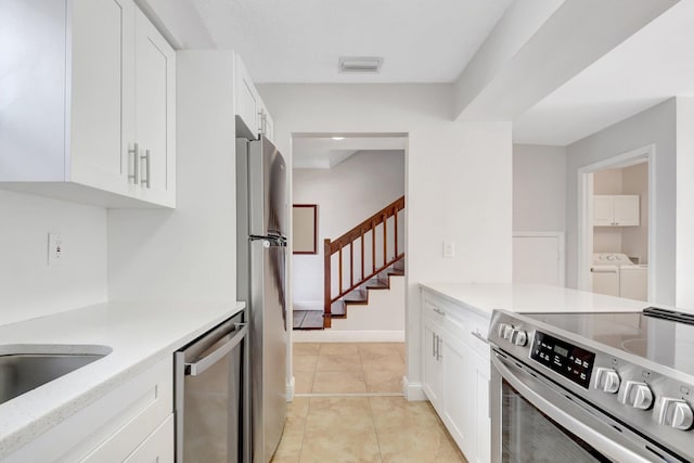 kitchen featuring white cabinetry, washing machine and clothes dryer, visible vents, stainless steel appliances, and light tile patterned flooring