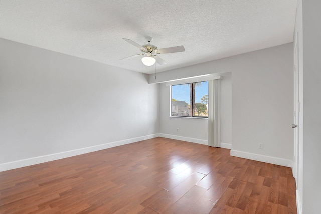 unfurnished room with a ceiling fan, a textured ceiling, wood finished floors, and baseboards