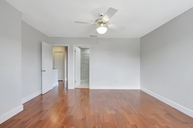 unfurnished room with wood finished floors, a ceiling fan, visible vents, and baseboards