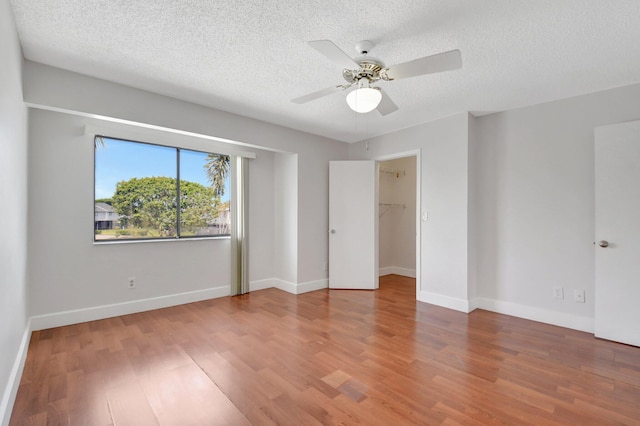 interior space with a textured ceiling, wood finished floors, ceiling fan, and baseboards
