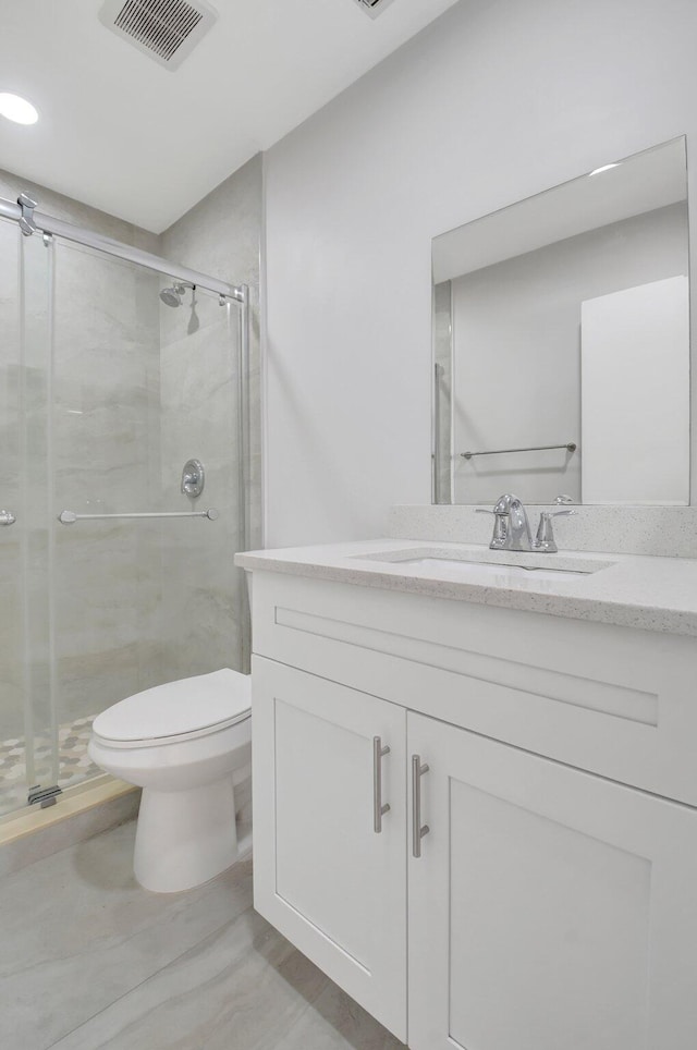 bathroom featuring toilet, visible vents, vanity, and a stall shower